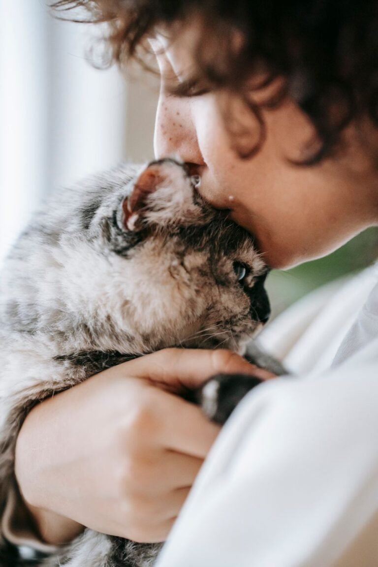 A young woman holding and kissing her cat