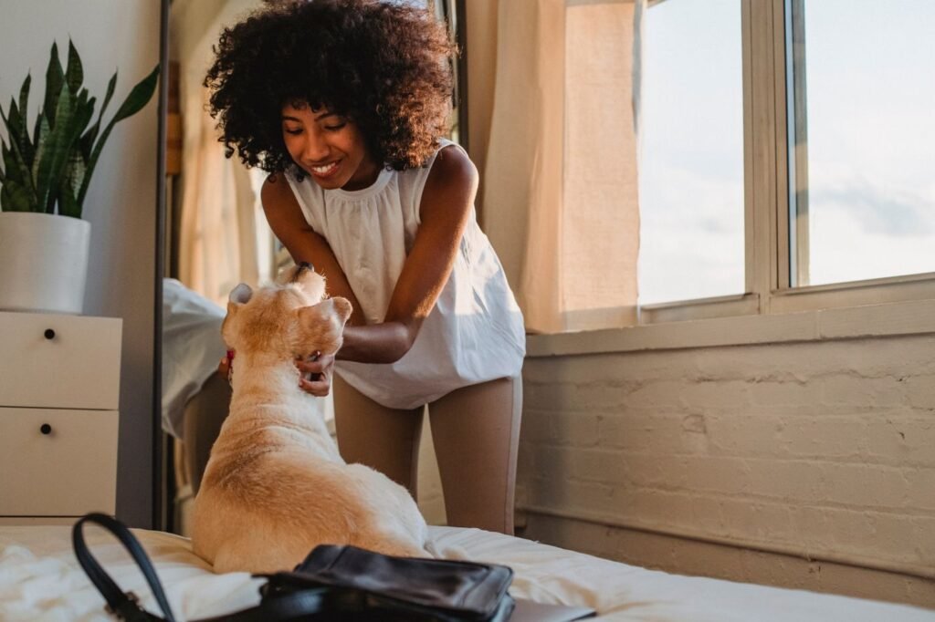 A woman laughing while playing with her dog at home